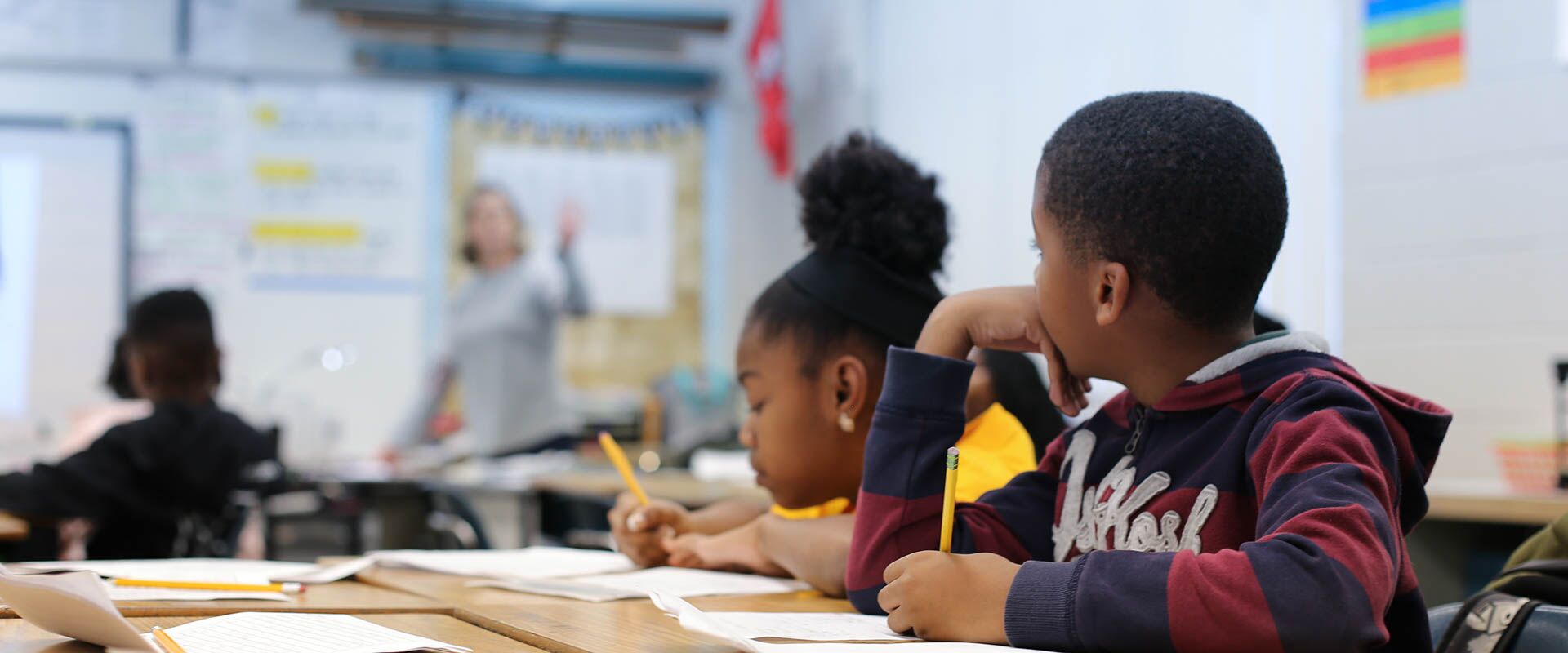 Dos niños en el aula, aprendiendo del maestro, escribiendo en papel en el escritorio, Hillsborough Education Foundation