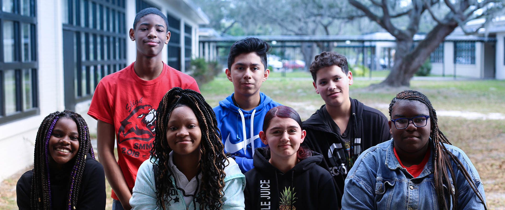 Group of 7 students standing outside in school courtyard, four people in front, three people standing behind, Hillsborough Education Foundation