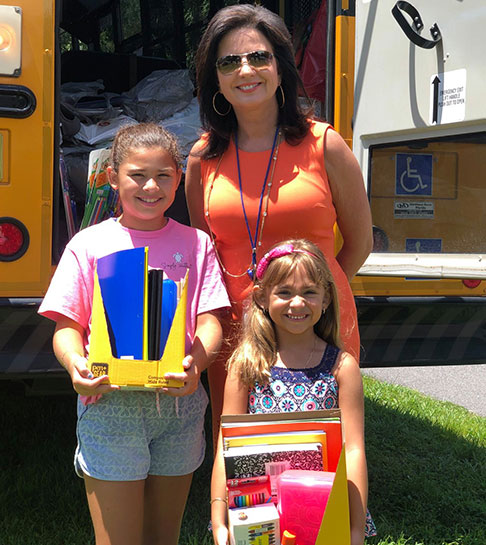 Mother and children showing school supplies collected for the Hillsborough Education Foundation