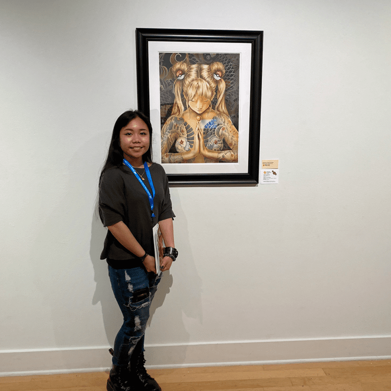 La estudiante posa con su pintura que fue seleccionada como nominada a American Vision